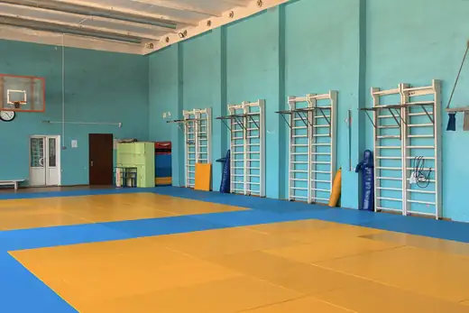 Trainingshalle mit gelben und blauen Matten und Sprossenw&auml;nden an der Wand