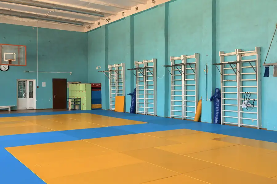 Trainingshalle mit gelben und blauen Matten und Sprossenwänden an der Wand
