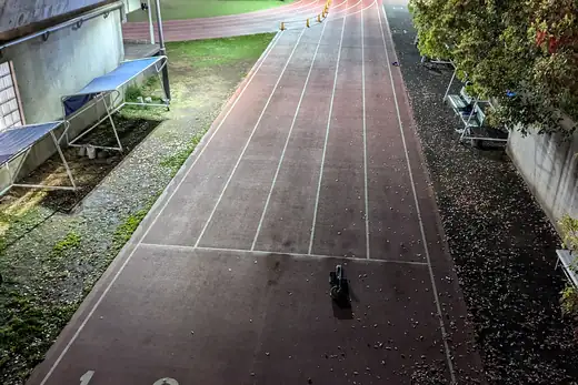 Leere Laufbahn am frühen Abend entlang einer Mauer