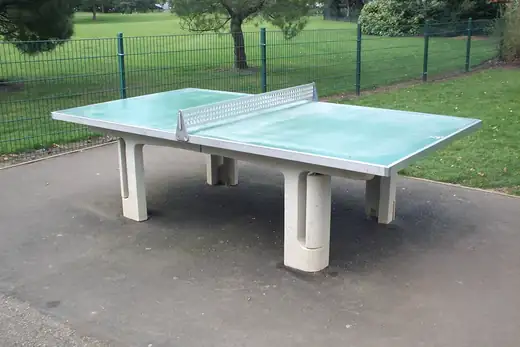 Tischtennistisch aus Beton im Freien, dahinter eine Rasenfl&auml;che