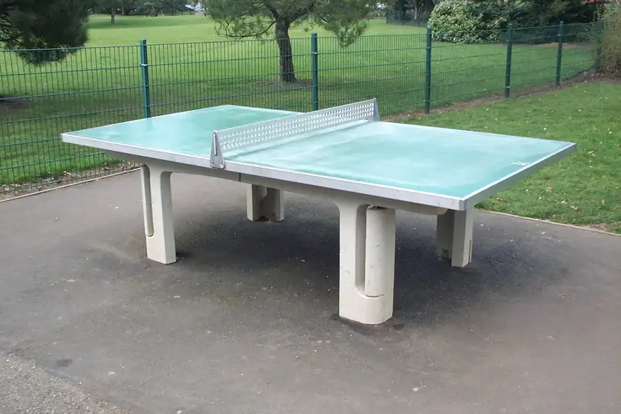Tischtennistisch aus Beton im Freien, dahinter eine Rasenfläche
